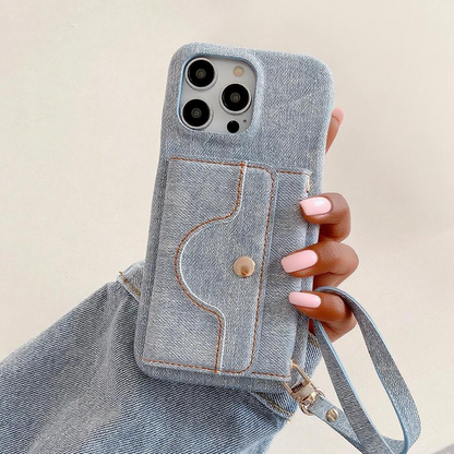 Denim phone case with a strap held by a hand against a beige background