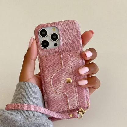 Pink denim phone case with a strap held by a hand against a beige background